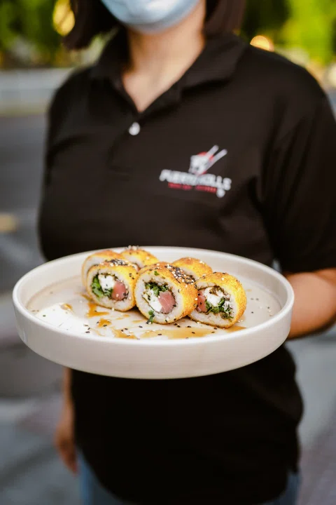 Plato de sushi sostenido por una persona de servicio.
