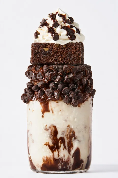 Milkshake de chocolate decorado con brownie, galletas y crema batida.