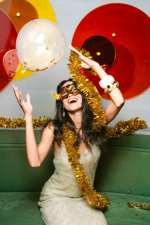 Mujer con antifaz festivo y globos.