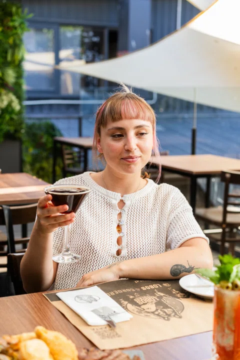 Mujer brindando con copa en terraza.