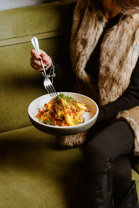 Mujer comiendo plato en ambiente de lounge.