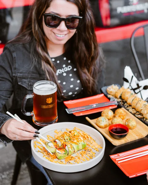 Mujer con gafas frente a bowl de comida y cerveza.