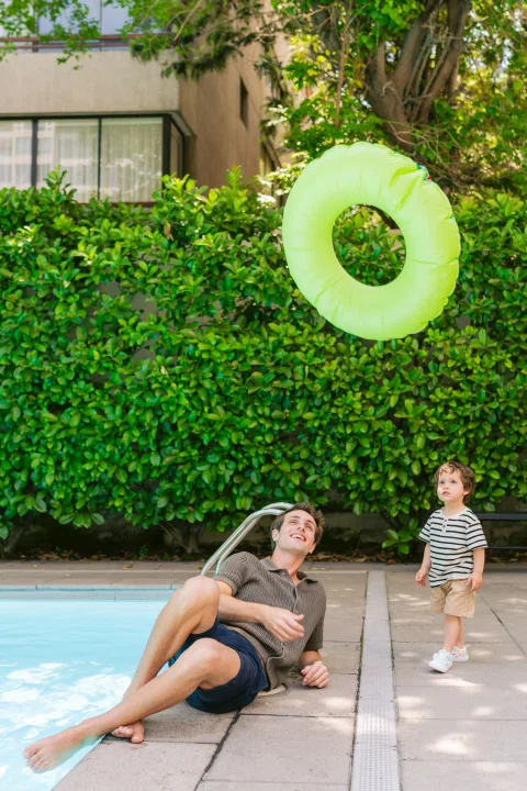 Mujer lanzando flotador verde junto a piscina.