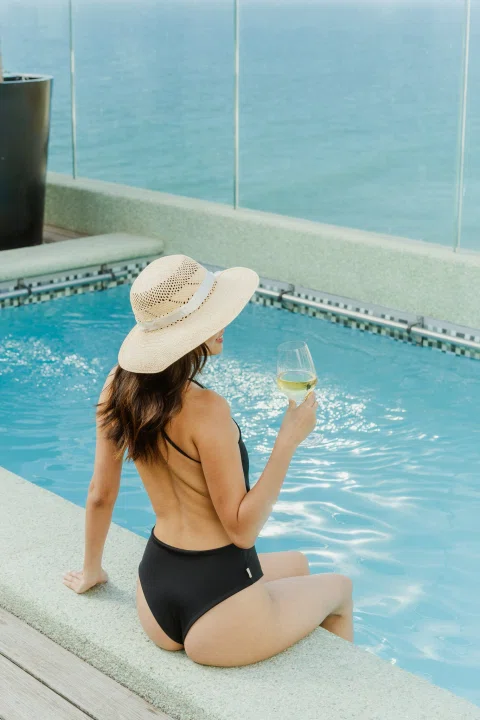 Mujer dentro de piscina exterior con sombrero.