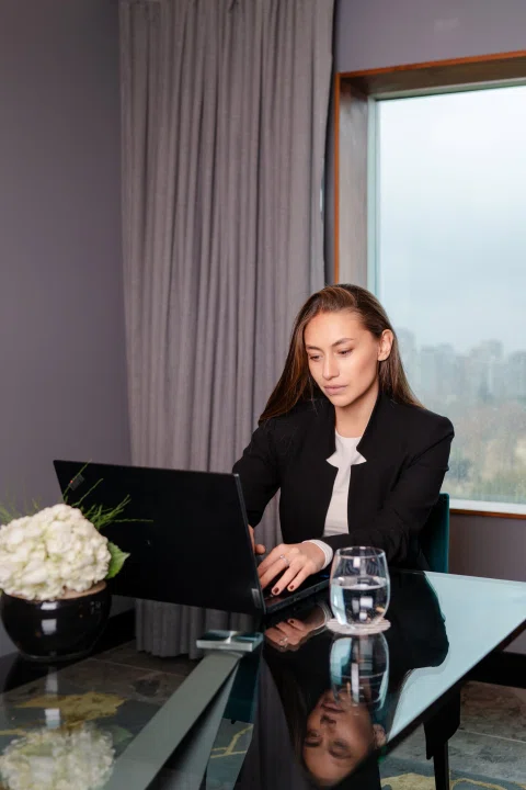 Mujer de traje trabajando en mesa junto a ventana.