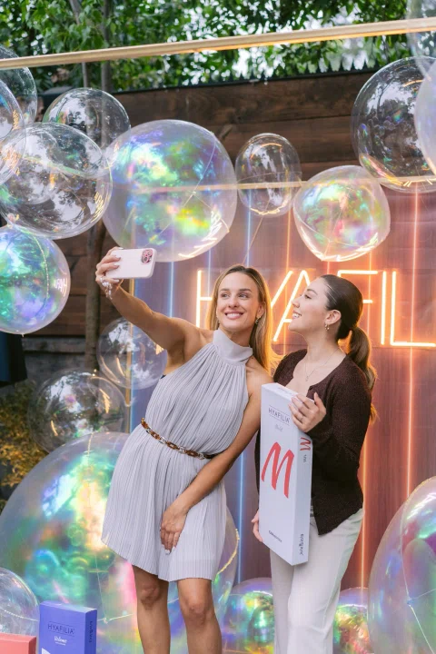 Dos mujeres participan en una experiencia con grandes burbujas durante un evento.
