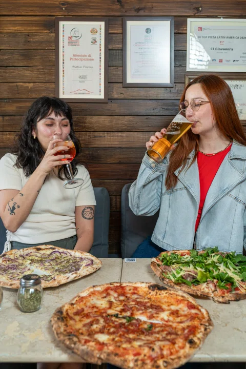 Mujeres conversando y comiendo pizza.