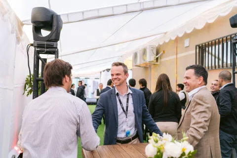 Invitados conversan bajo una carpa durante un evento exterior.