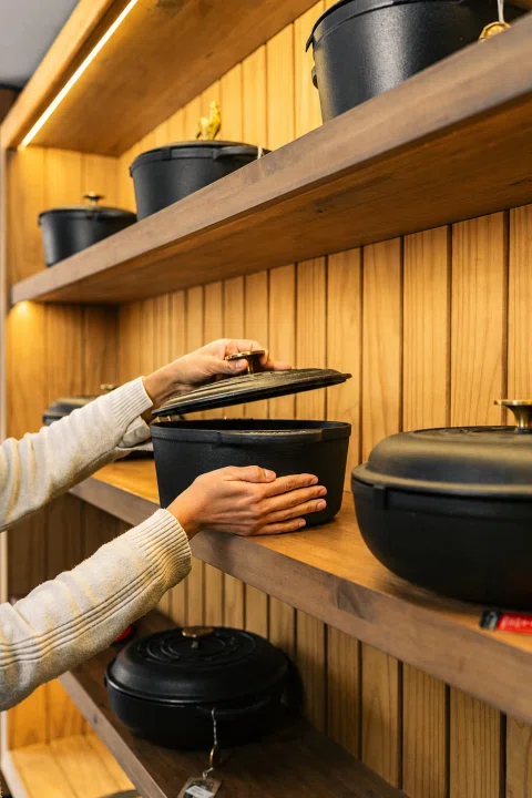 Olla negra presentada frente a una exhibición de cocina.
