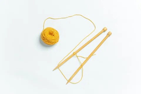 Ovillo amarillo con agujas de tejer.
