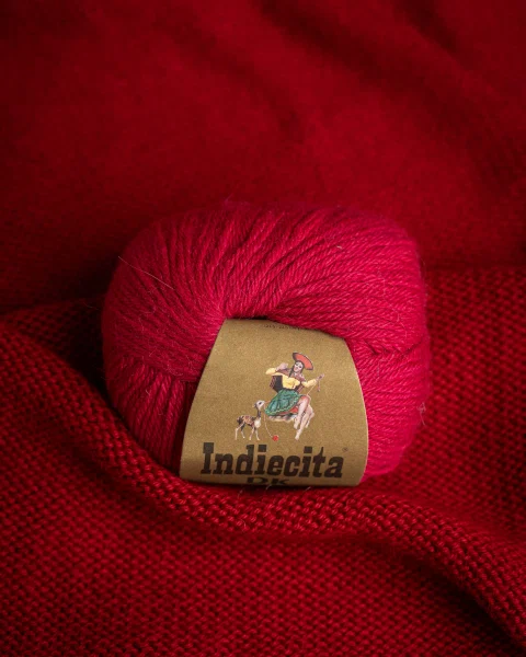 Ovillo fucsia aislado sobre tela roja.