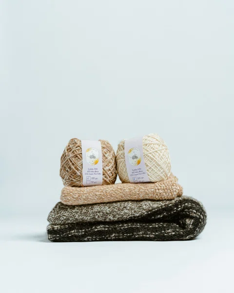 Ovillos beige apilados sobre textiles tejidos.