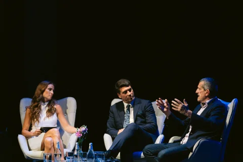 Tres participantes conversan en un panel sobre escenario.