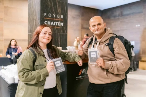 Dos asistentes posan con sus credenciales en el foyer.