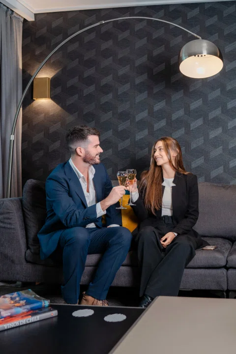 Pareja brindando sentada en lounge oscuro.