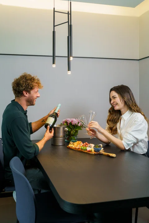 Pareja compartiendo comida en mesa de habitación.