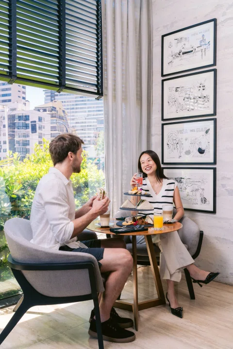 Pareja conversando en mesa junto a mural.