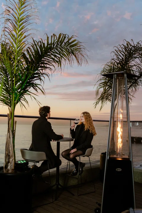 Pareja conversando en terraza al atardecer.