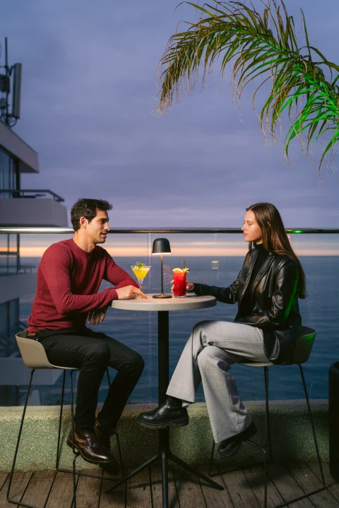 Pareja conversando en terraza con cócteles.