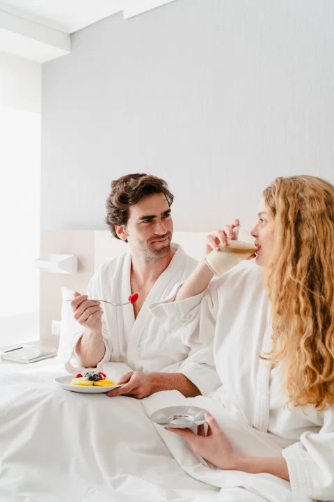 Pareja desayunando con batas en habitación.