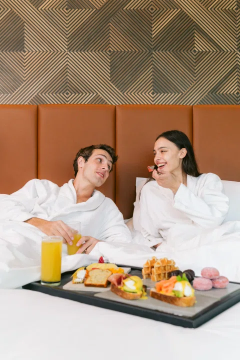 Pareja desayunando en cama con bandeja.