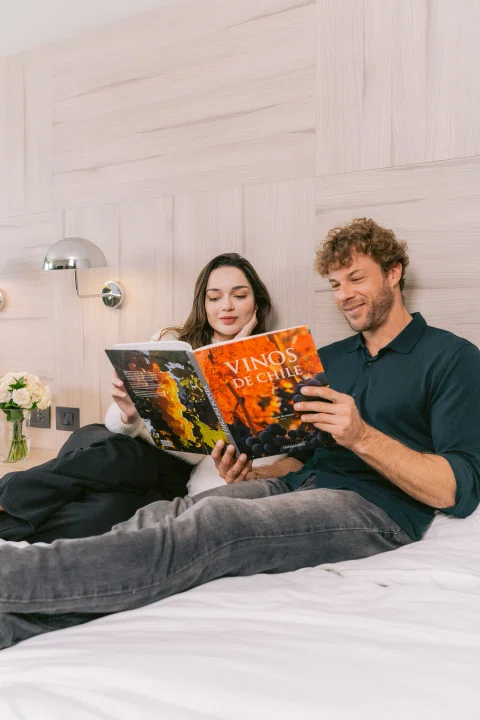 Pareja leyendo revista sobre cama.