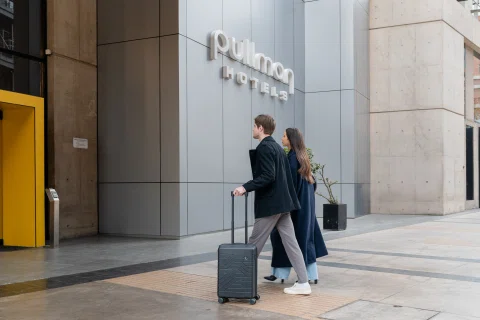 Pareja llegando con maleta a entrada Pullman El Bosque.