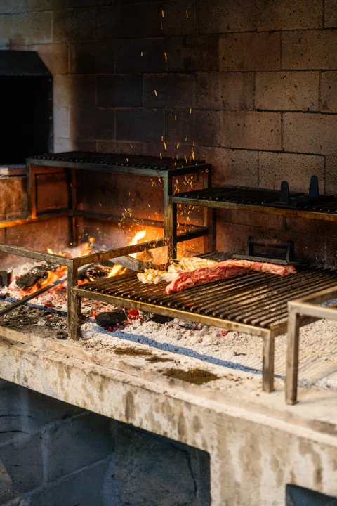Parrilla encendida con carnes sobre las brasas.