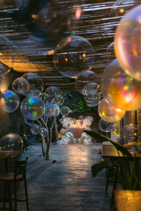 Pasillo de evento decorado con globos e iluminación cálida.
