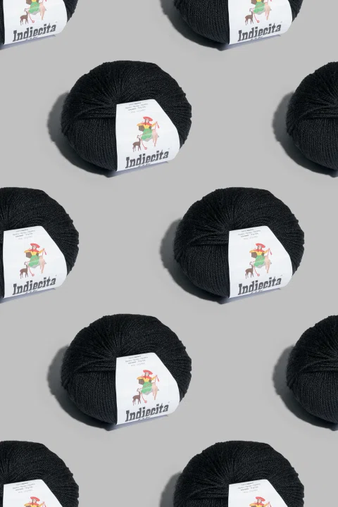 Patrón gráfico con ovillos negros sobre fondo gris.