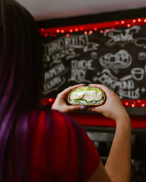 Persona comiendo roll tipo burrito frente a muro ilustrado.