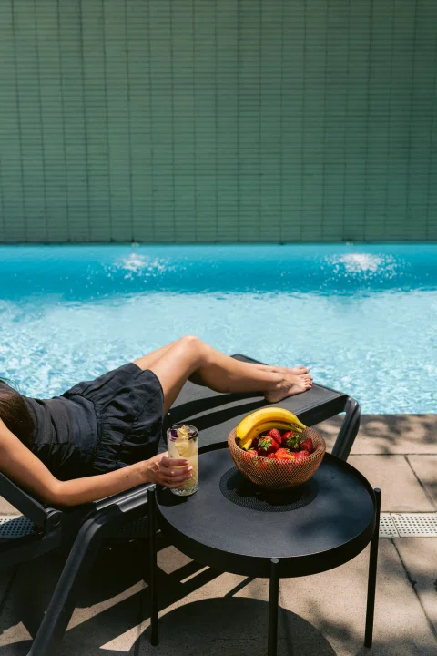 Persona descansando junto a piscina con aperitivo.