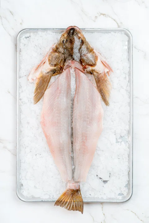 Pescado abierto sobre bandeja transparente con hielo.