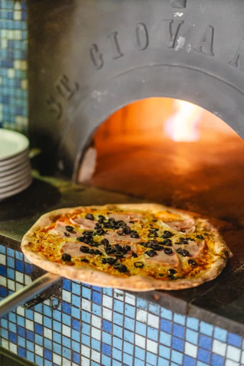 Pizza dentro del horno de piedra encendido.