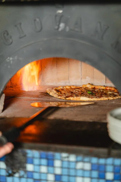 Pizza dentro del horno de piedra con llamas.