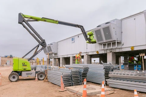 Plataforma elevadora operando junto a módulo industrial.