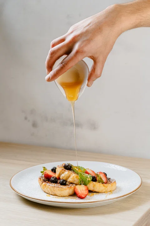 Mano vierte salsa sobre un plato de mariscos.