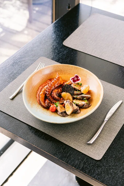 Plato de pulpo servido sobre mesa exterior.