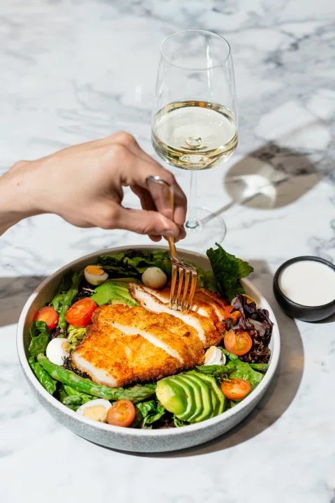 Ensalada con salmón acompañada de una copa de vino.