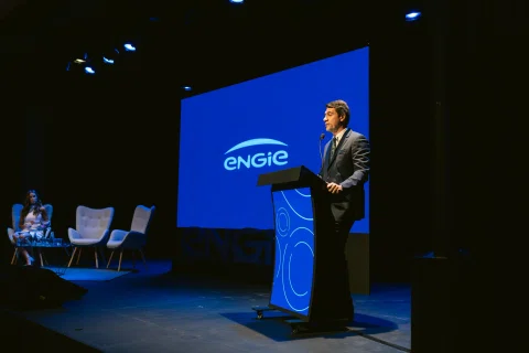 Ponente habla desde un podio en un escenario corporativo.
