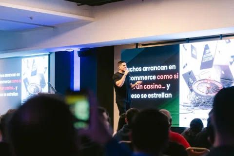 Ponente realiza una presentación frente a una pantalla con contenido de comercio electrónico.