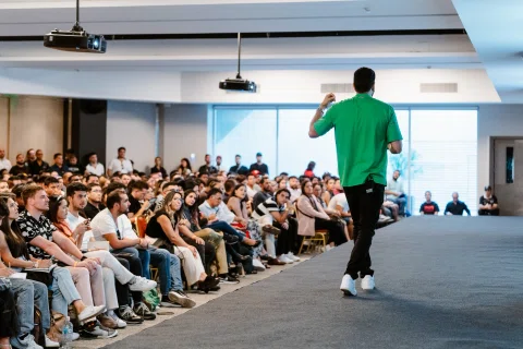 Ponente con camiseta verde habla frente a una audiencia.