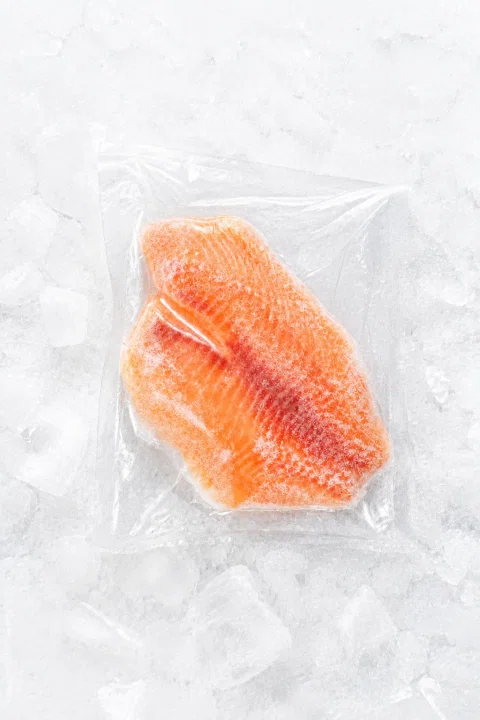 Porción de salmón en envase transparente sobre hielo.