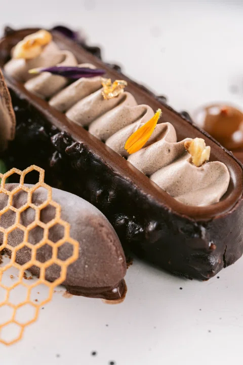 Postre alargado con chocolate y decoración.