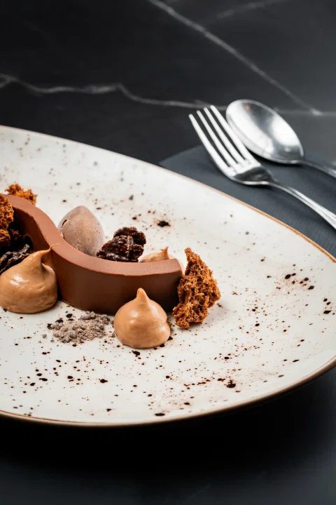 Postre de chocolate con quenelles y migas.