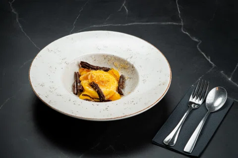 Postre con frutas y crema en plato blanco.