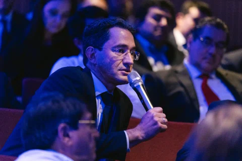 Asistente formula una pregunta con micrófono desde el público.