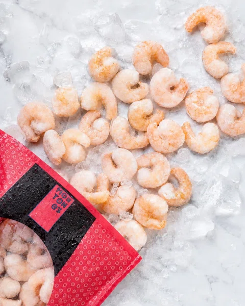 Producto alimenticio congelado sobre hielo junto a su envase.
