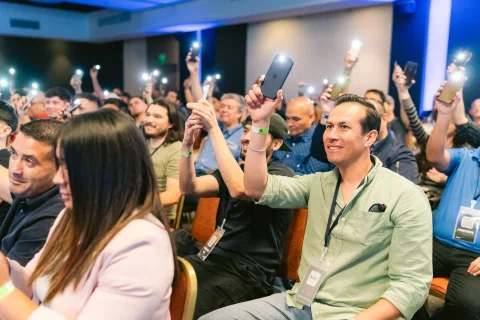 Público sentado levanta teléfonos durante una presentación.