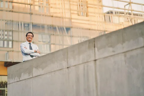 Retrato corporativo de un hombre con camisa blanca en una locación arquitectónica.